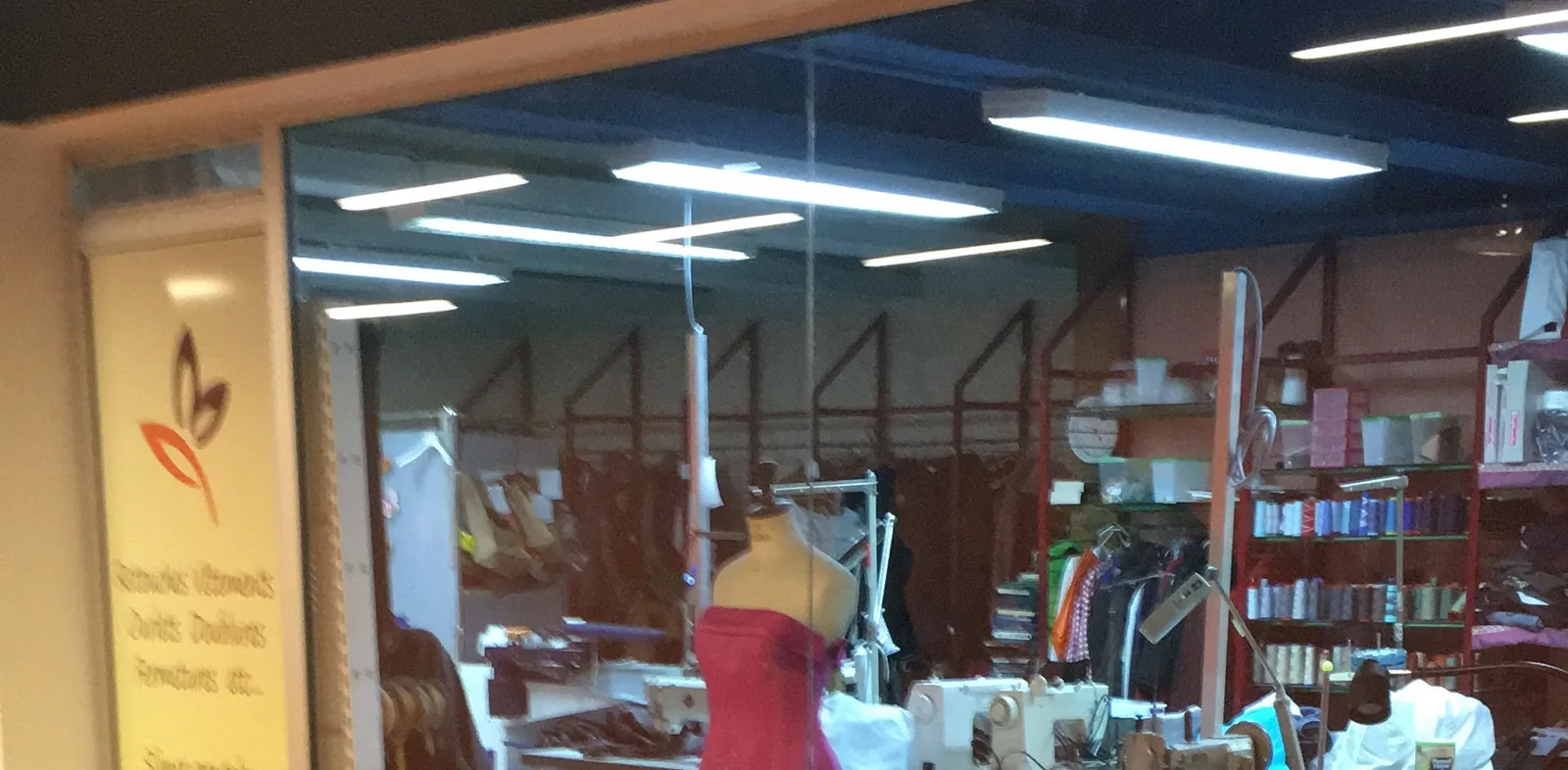 L&rsquo;atelier vu de la galerie du centre Beaulieu : machines à coudre, étagères de bobines de fil et mannequin de couturière habillé d&rsquo;une robe rose