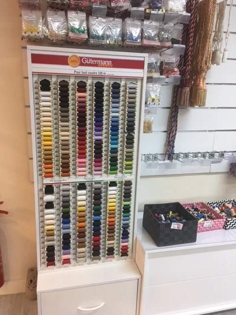 Présentoir de fils à coudre Gütermann, rangés par teinte, dans la mercerie de l'atelier